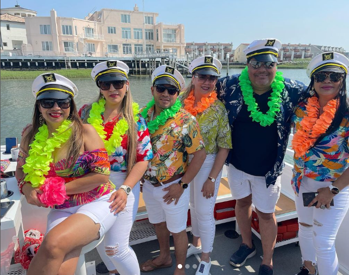 Group of people in captain hats and leis on a boat, posing for a photo.