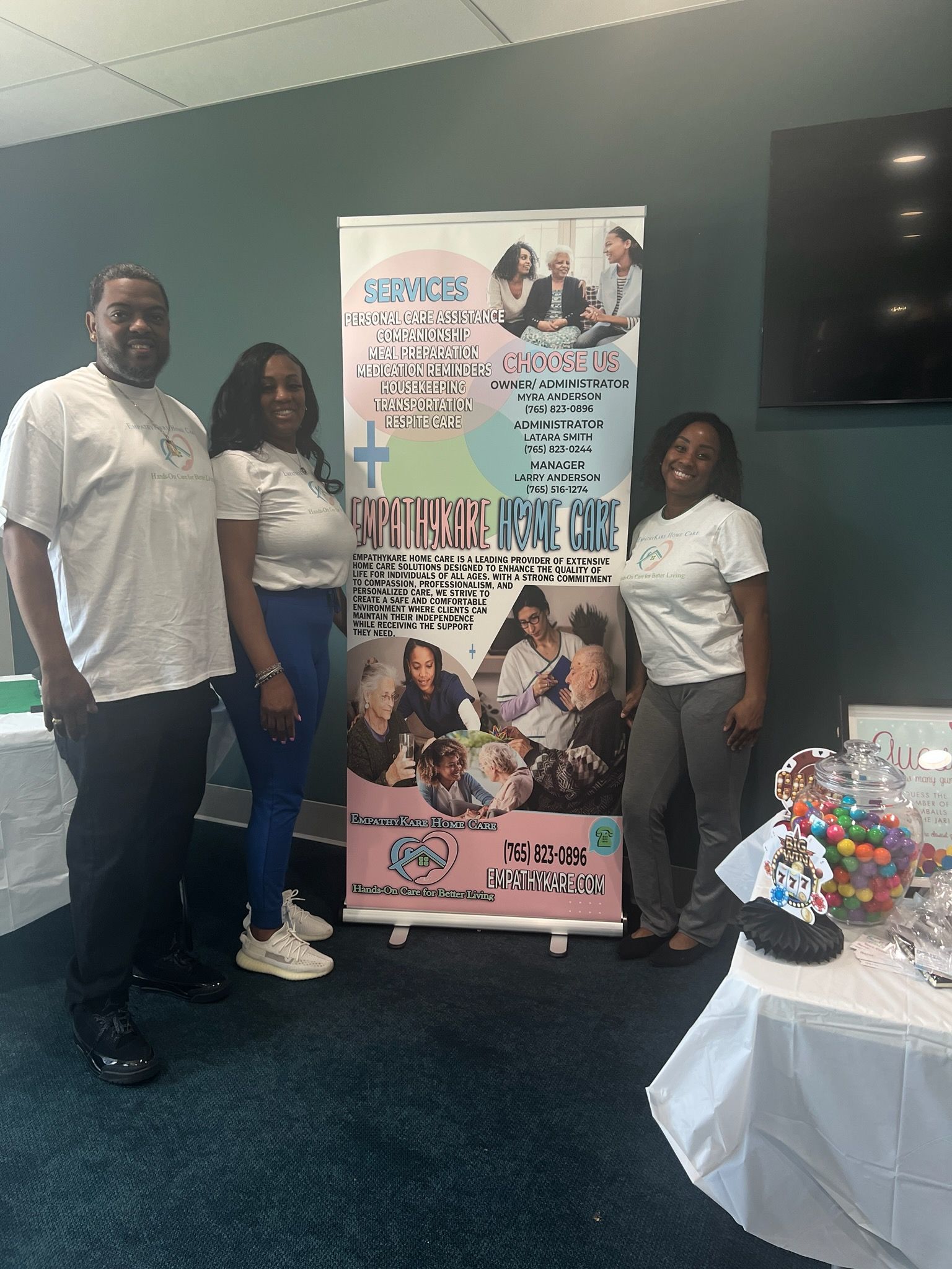 Three people stand by a banner promoting
