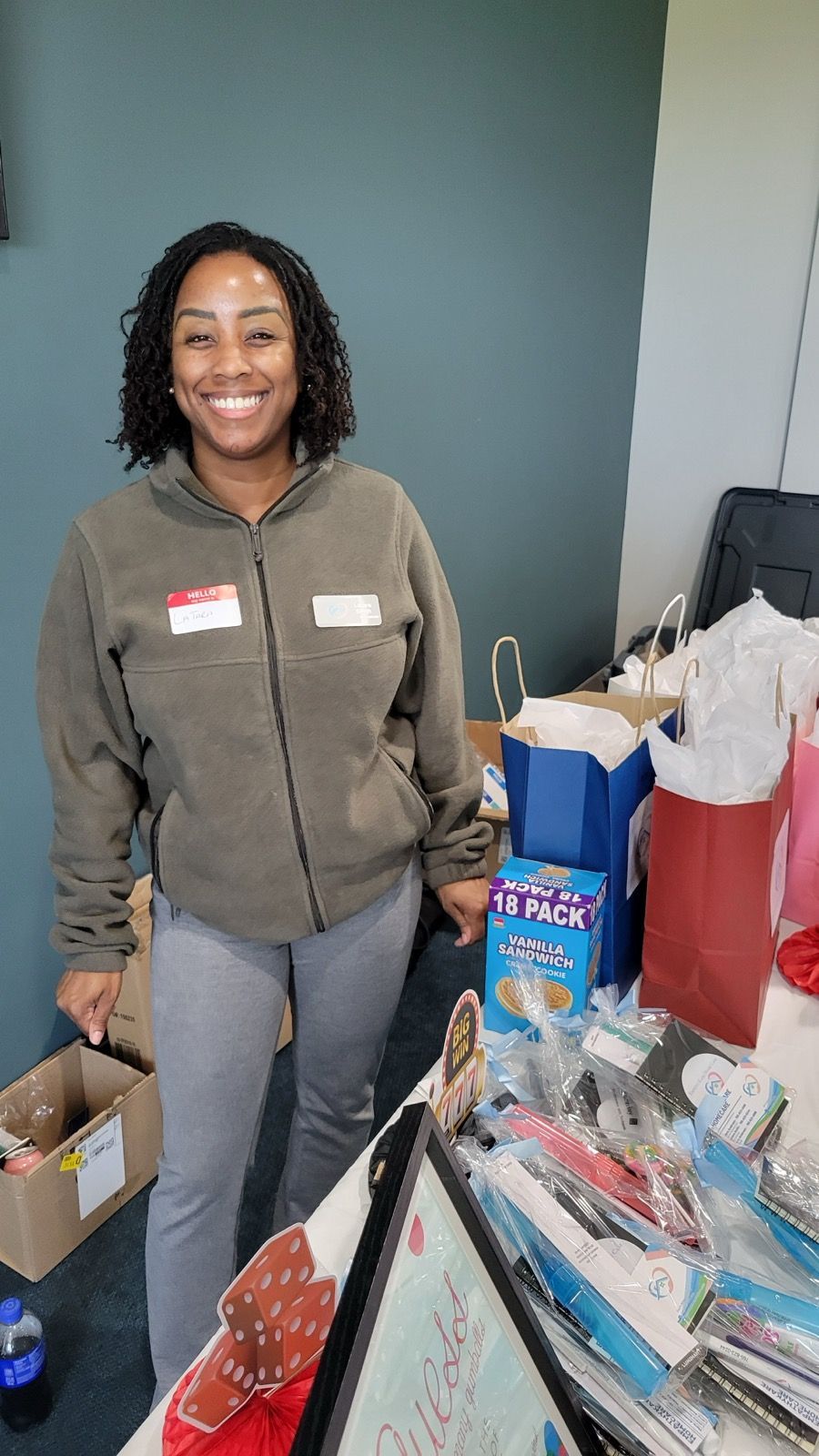Woman smiles in front of a table with gifts and a box