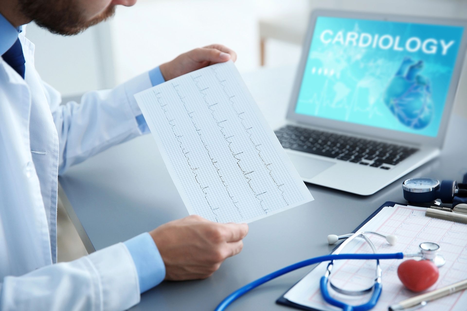 Un médico sostiene un trozo de papel delante de una computadora portátil.