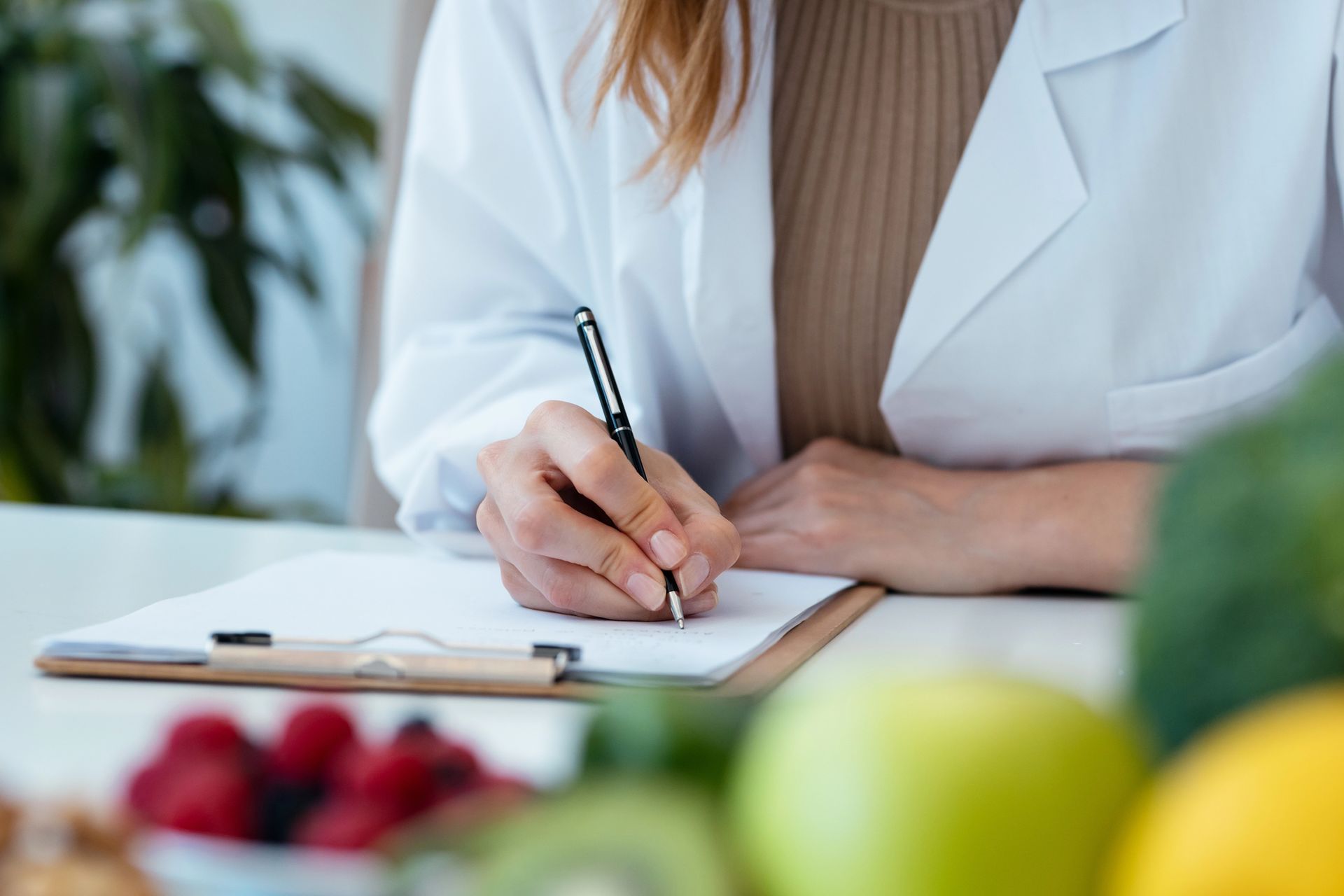 Una mujer está sentada en una mesa escribiendo en un portapapeles.