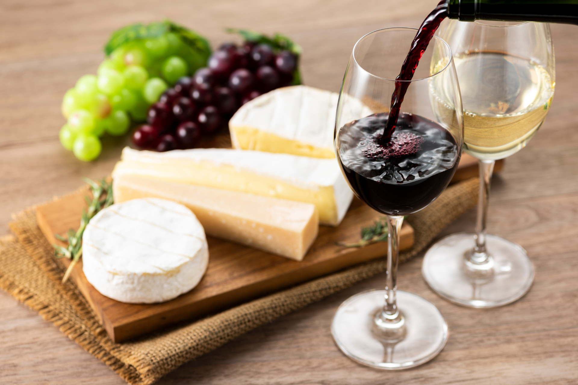 Red wine pouring next to cheese and grapes during tasting at Nemea