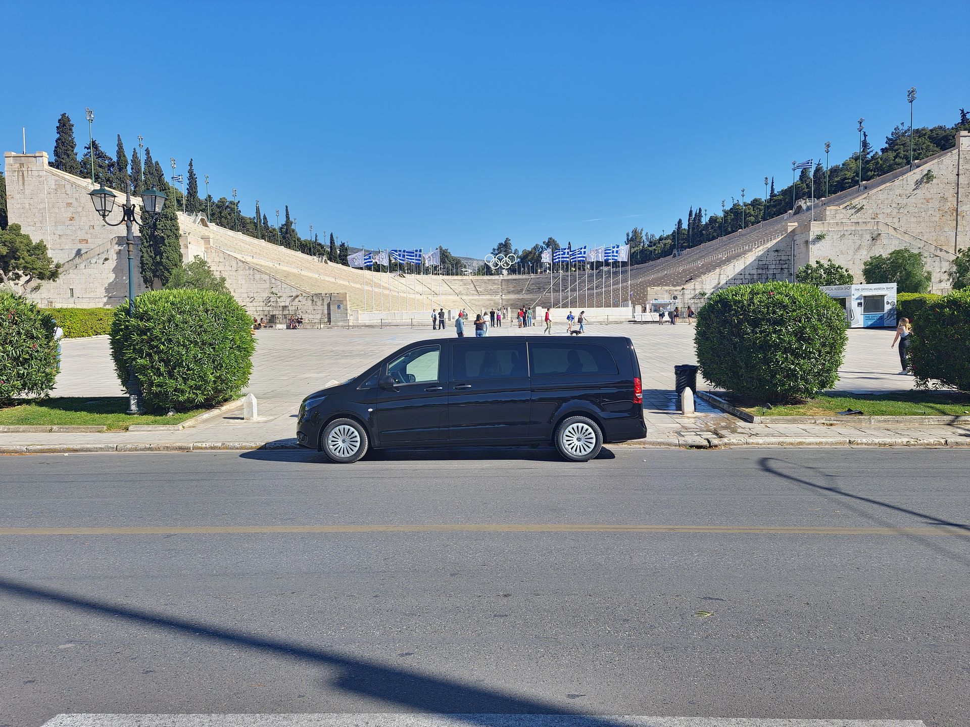 Athenaos Travel & Tours black Mercedes van in front of the Panathenaic Stadium (Kallimarmaro) in Athens.