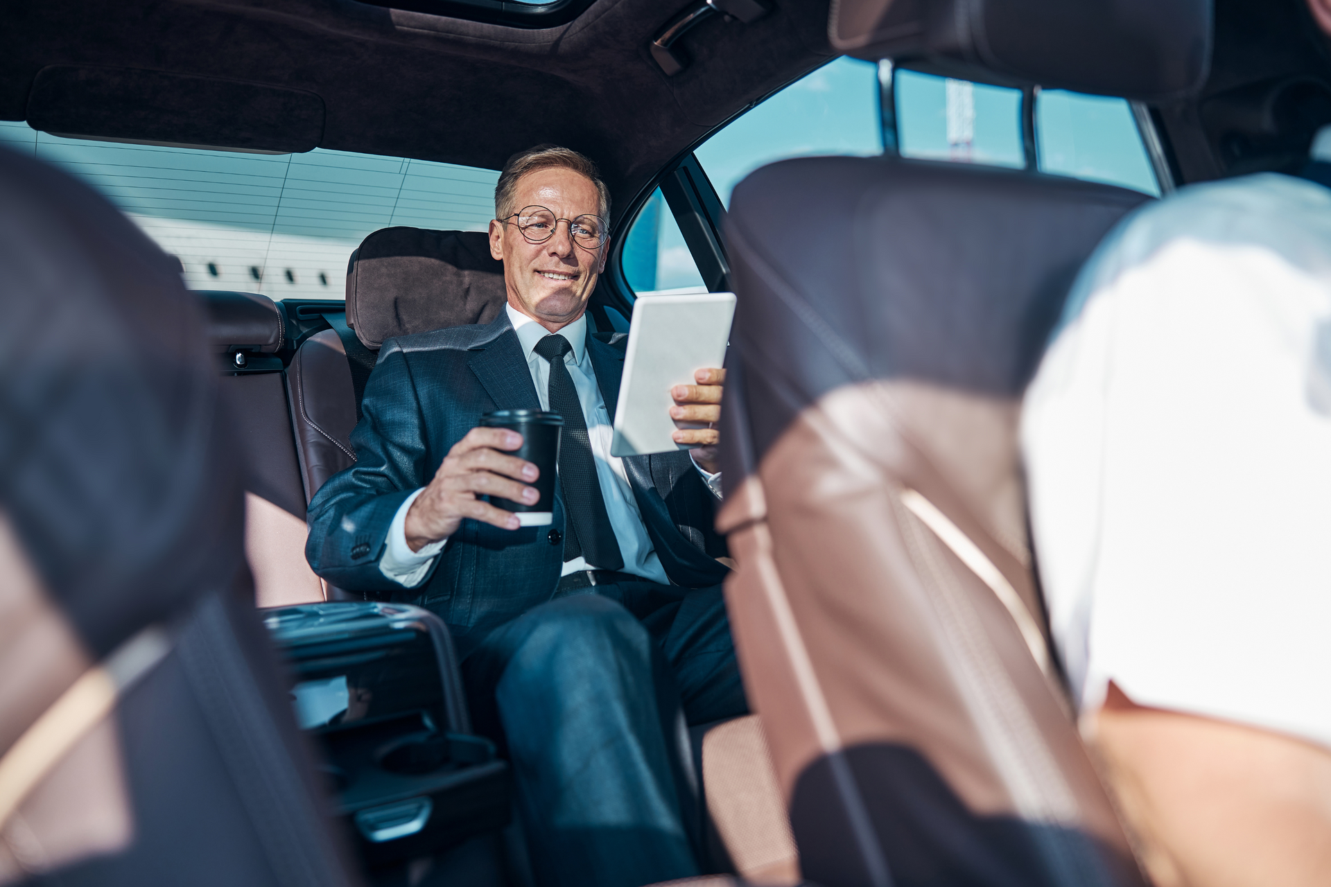Ein Geschäftsreisender fährt während eines privaten Transfers in einem luxuriösen Mercedes mit professionellem Fahrer.