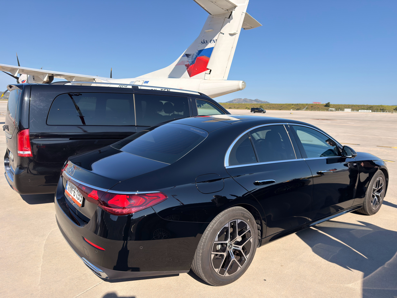 Athenaos Travel & Tours Mercedes luxury minivans parked at an airport hangar beside a private jet.