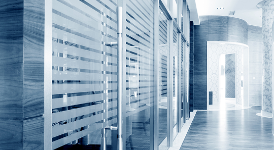 Modern office interior with frosted glass partitions, wooden walls, and polished flooring in cool blue tones.