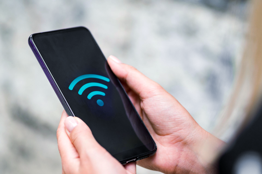 Hands holding a smartphone displaying a Wi-Fi signal icon.