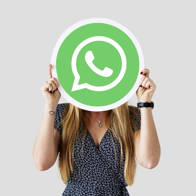 Mujer sosteniendo el logotipo de WhatsApp frente a su cara.