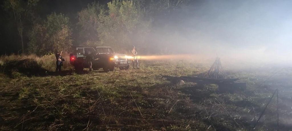 A group of people are standing in a field at night.
