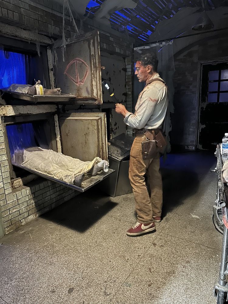 A man is standing in a dark room looking at a tablet.