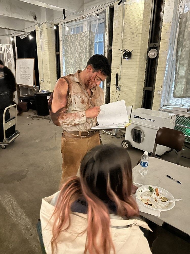 A man is writing on a piece of paper while a woman sits at a table.