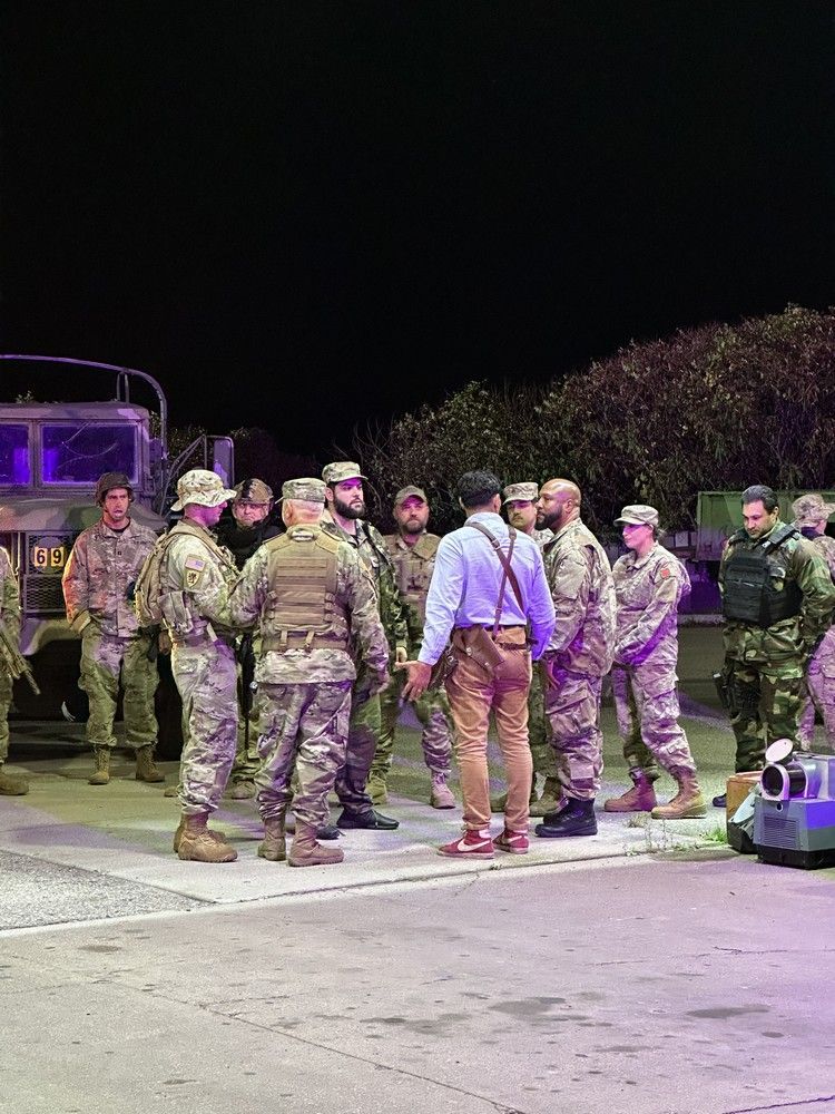 A group of soldiers are standing on the side of the road at night.