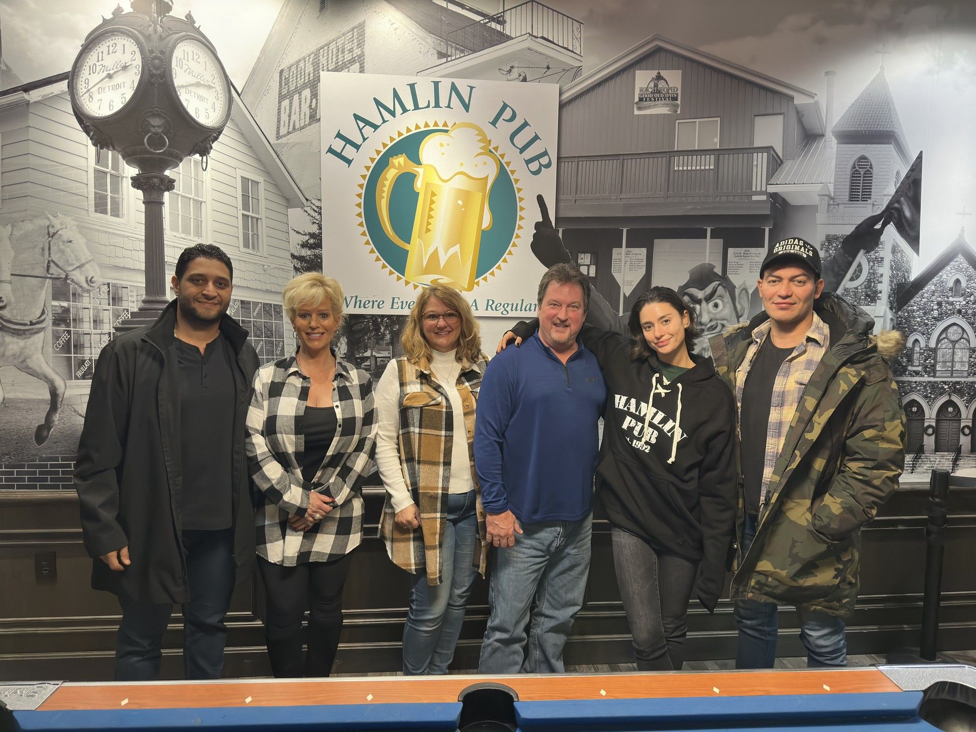 A group of people are posing for a picture in front of a pool table.