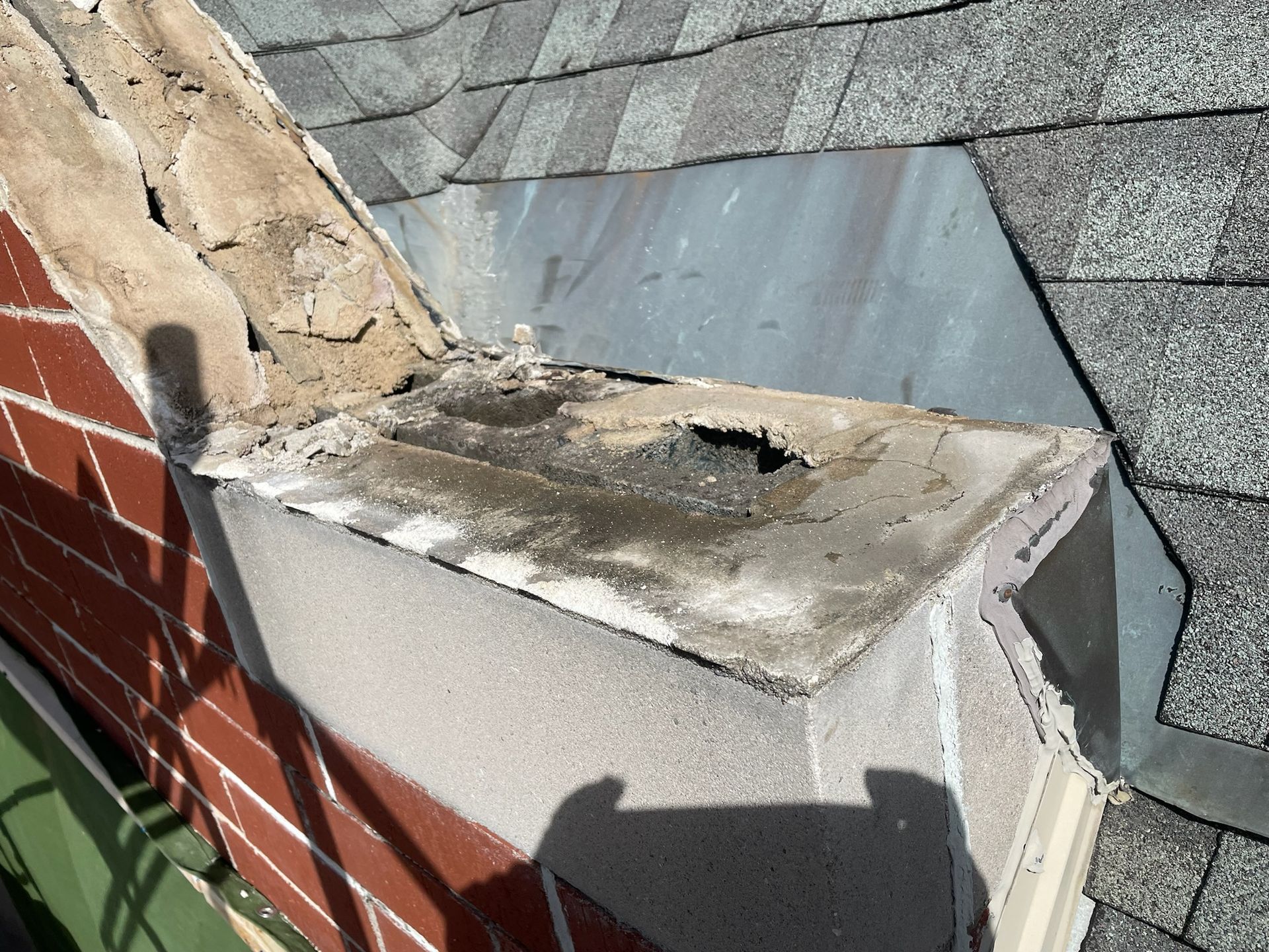 Very damaged and wet capstone on top of parapet wall on shingled roof