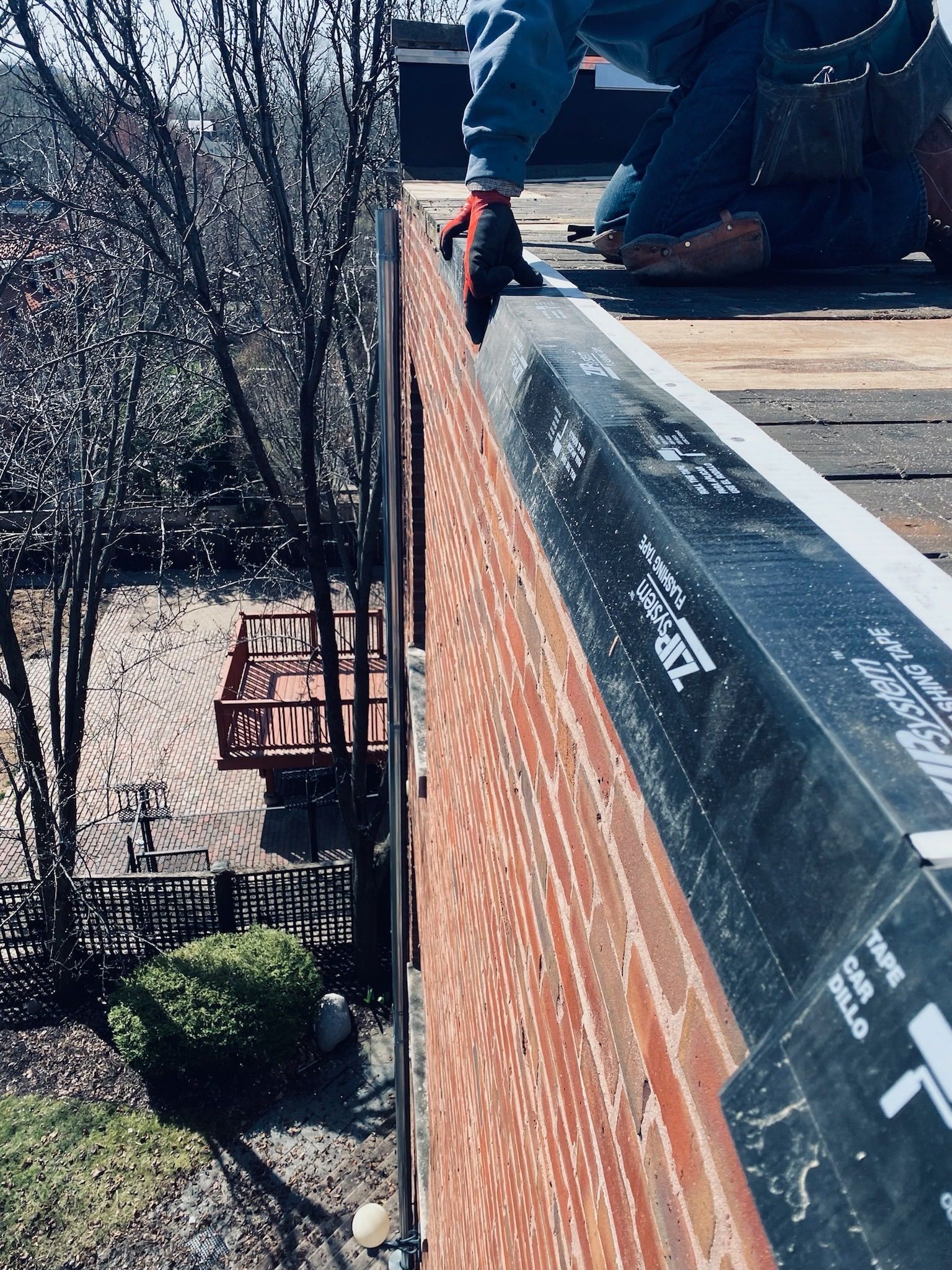 Worker installing perimeter vent on a sloped brick roof