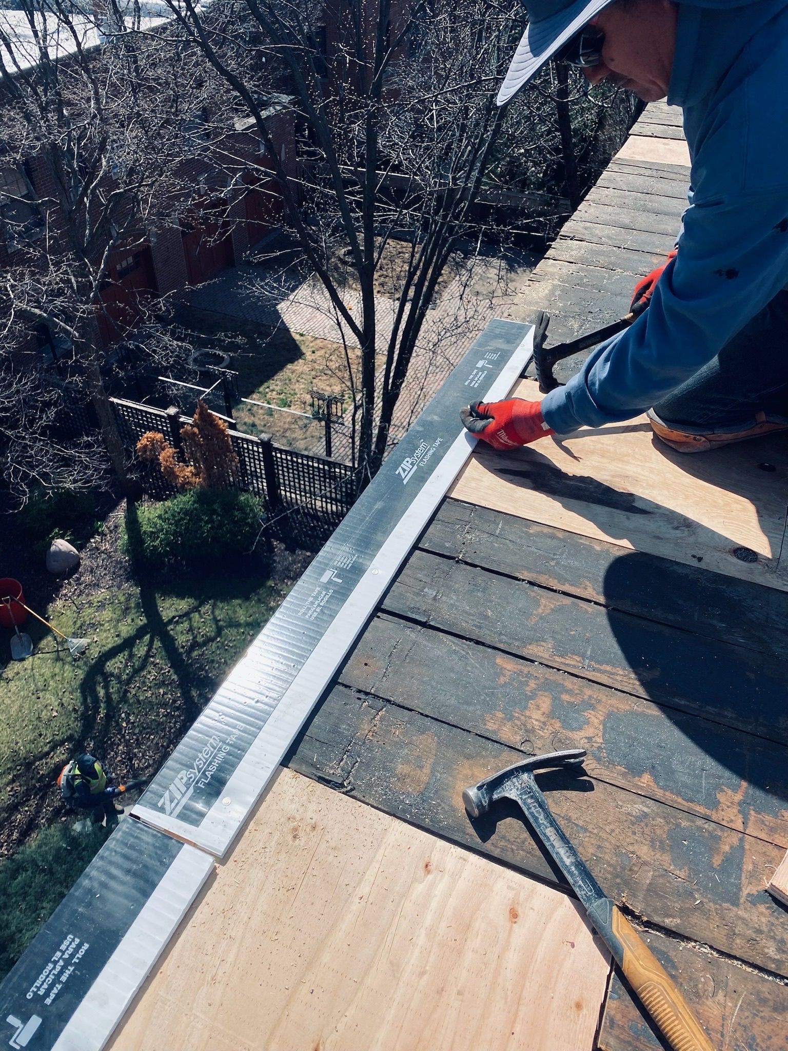 Worker nailing perimeter vent on side of rooftop