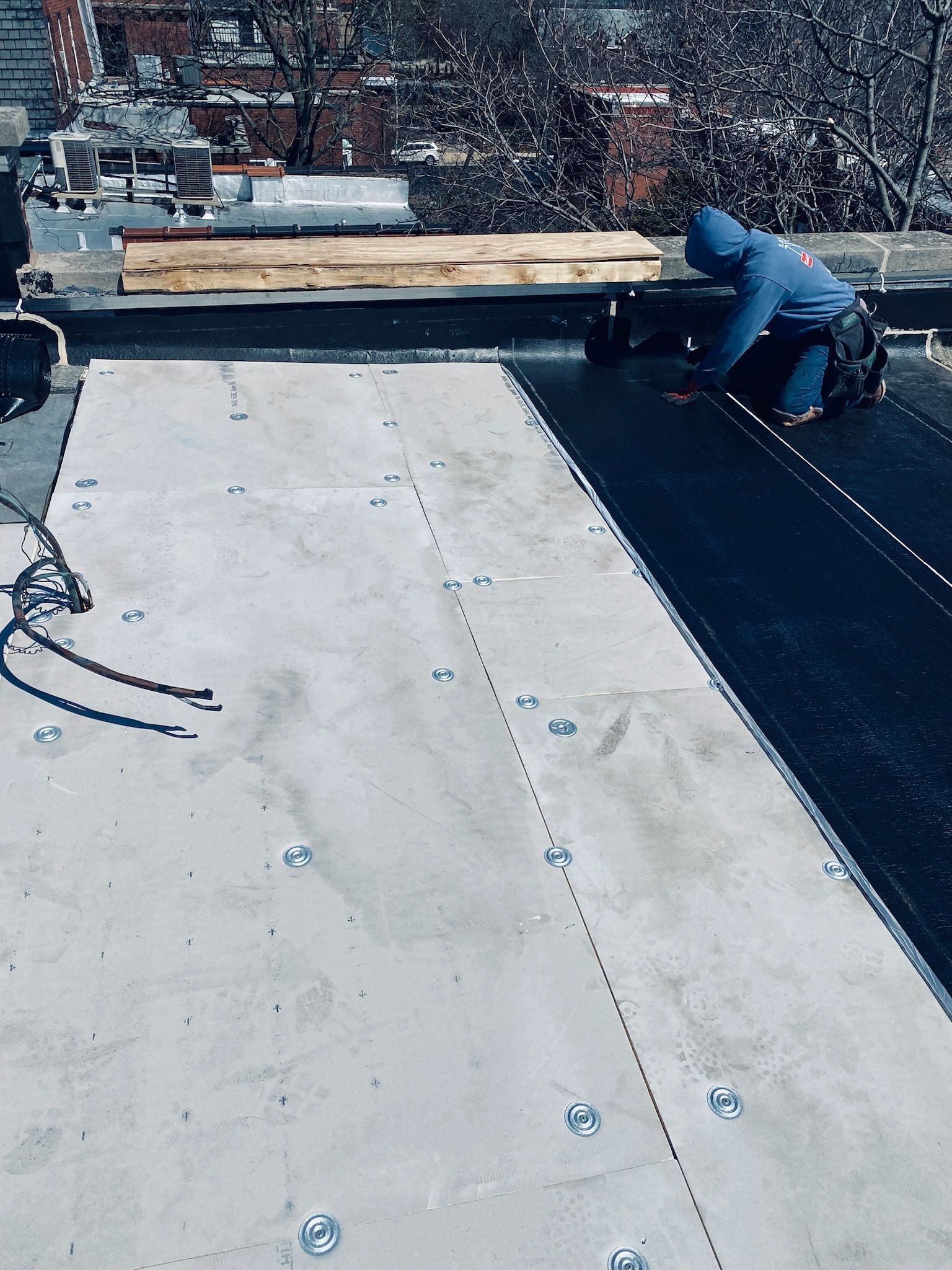 Worker installing roof membrane on rooftop floor
