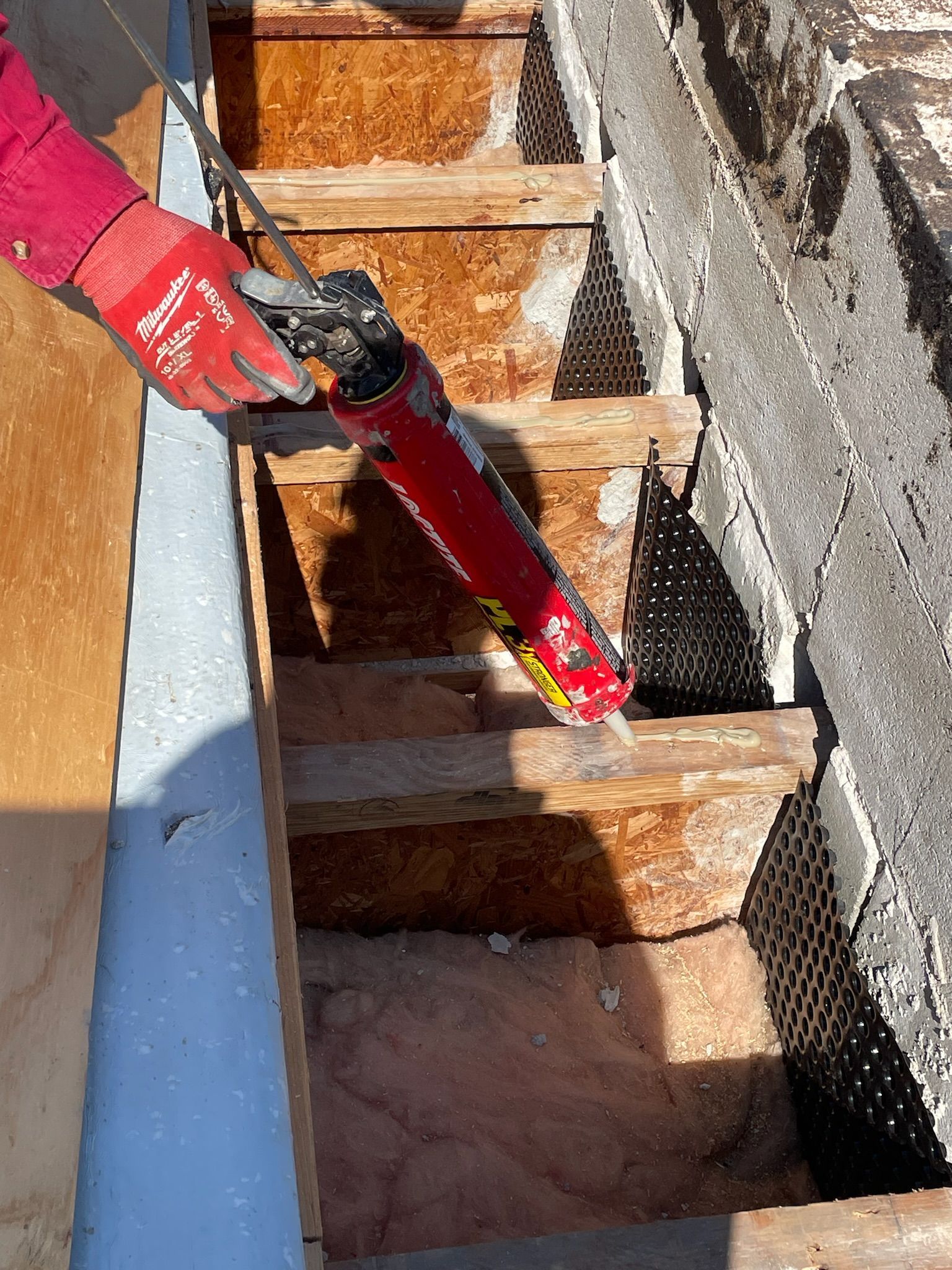 Worker applying caulk on top of trusses