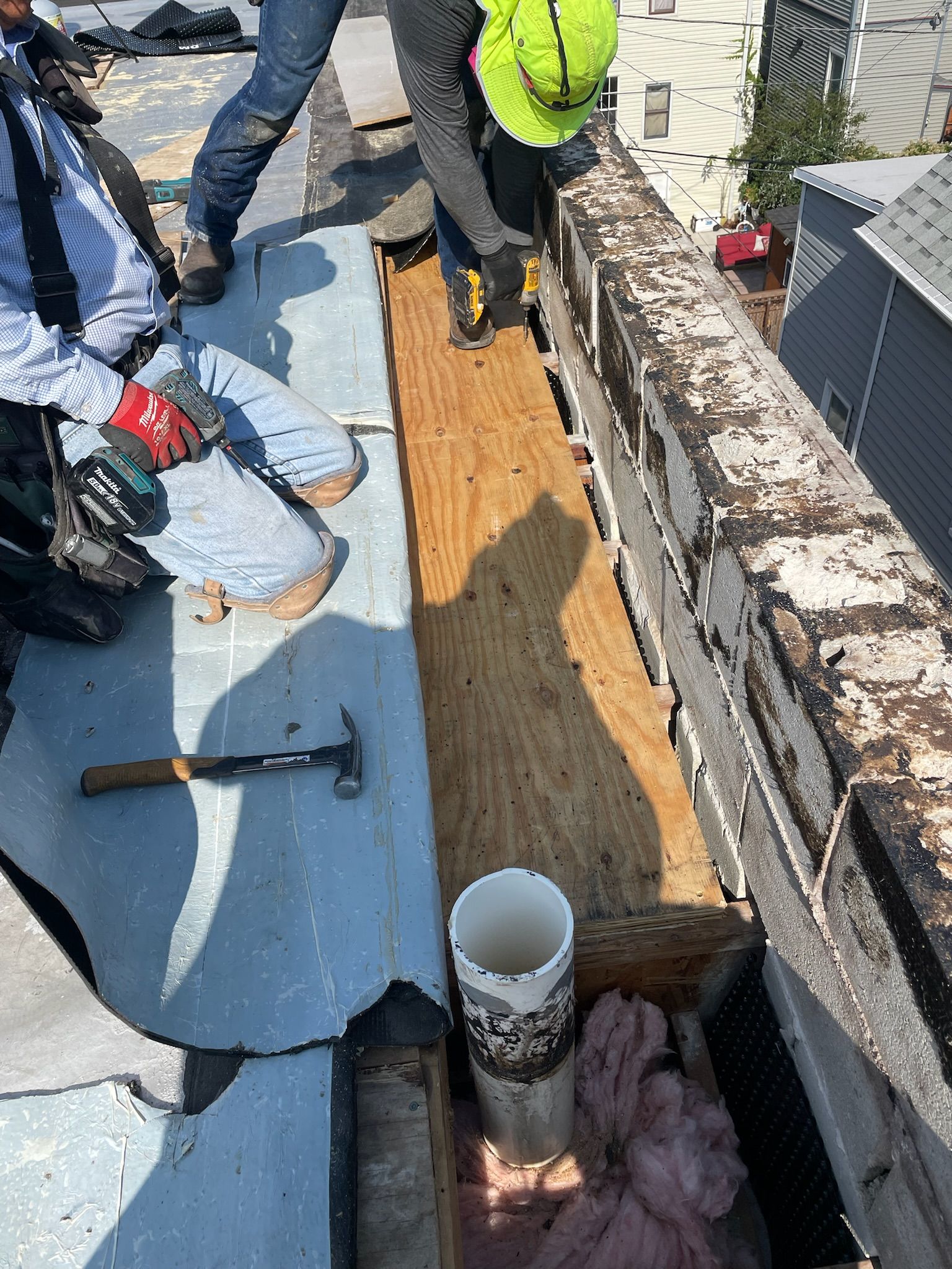 Workers on a rooftop done installing plywood base on top of trusses