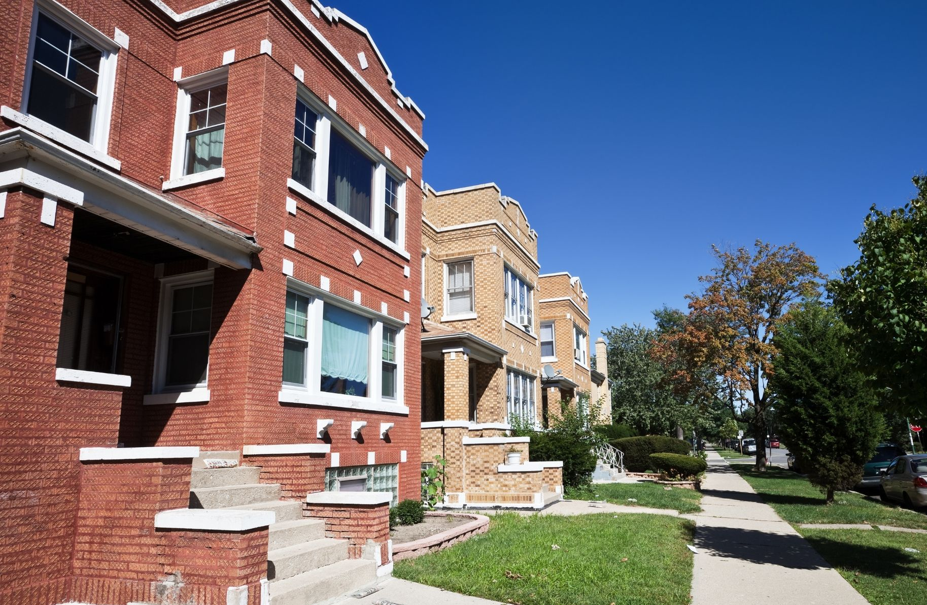 Brick apartment buildings along a sidewalk with green lawns