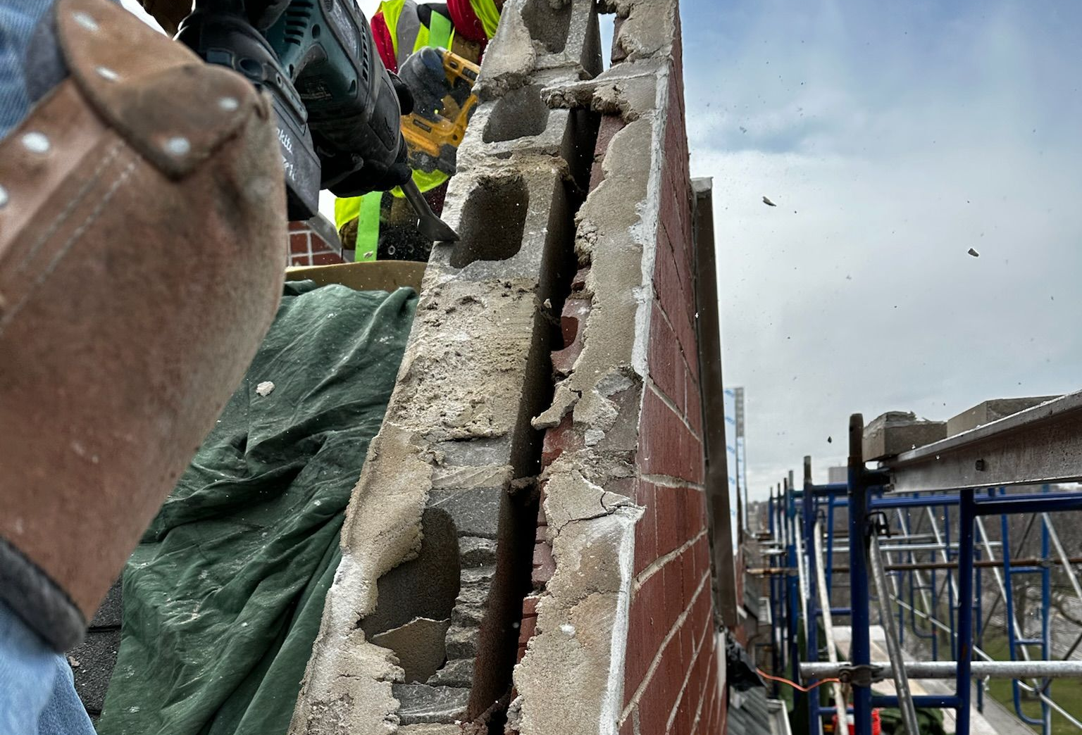 Brick wall with exposed rubble beside scaffolding at a construction site
