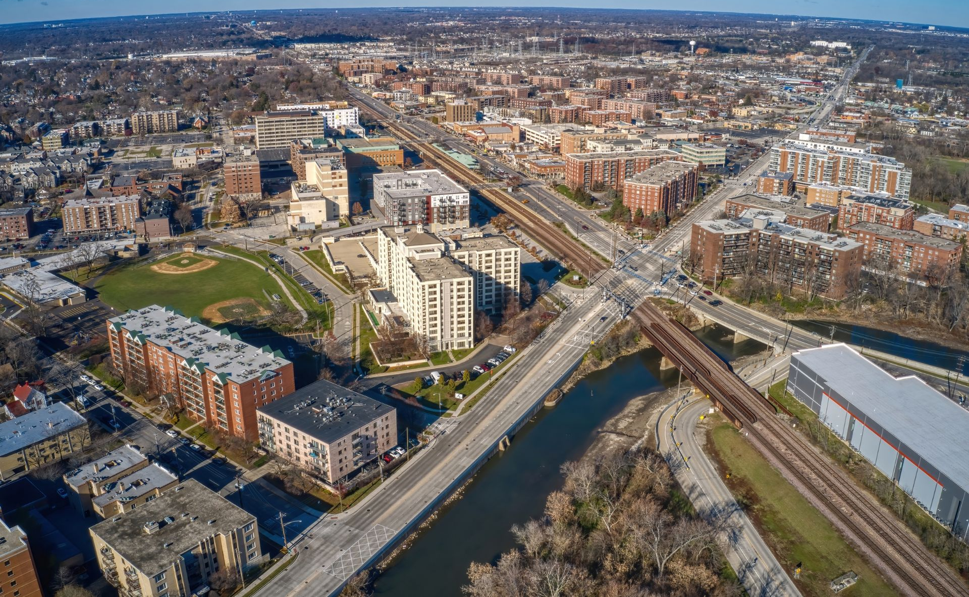 Aerial view of a city with rail tracks, roads, apartment buildings, and a green park area