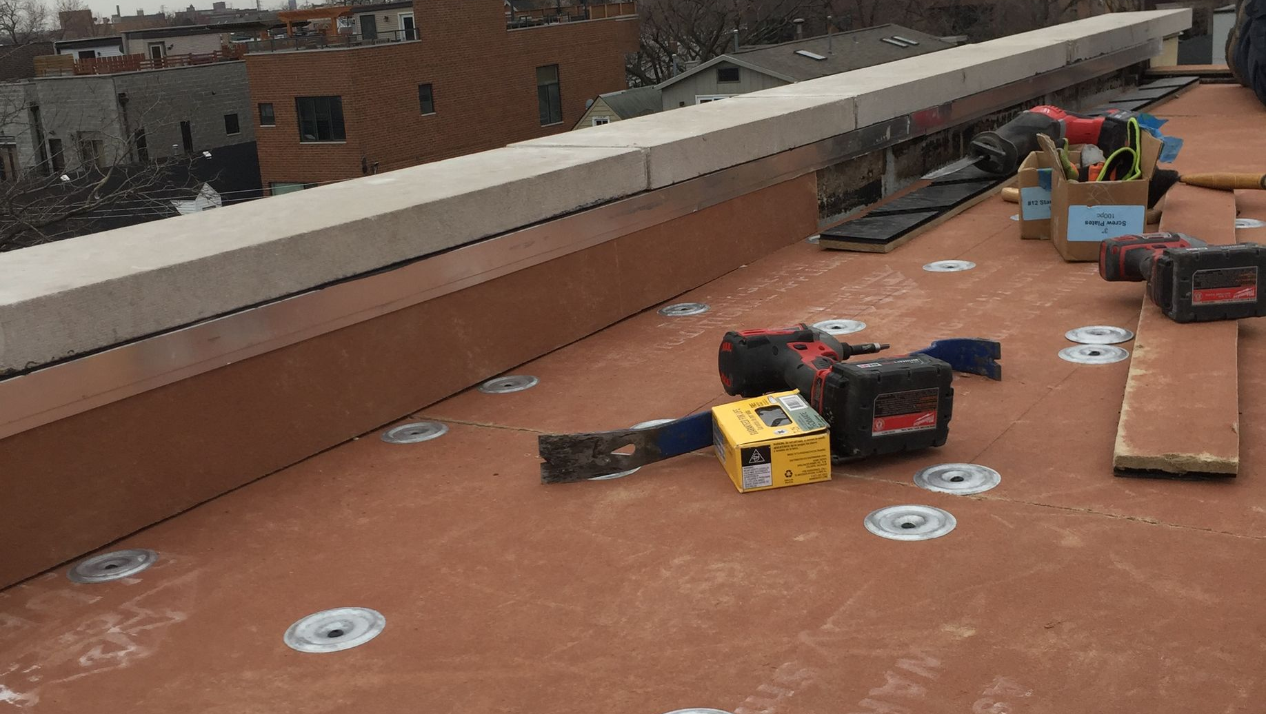 Rooftop with scattered tools and boxes beside a low brick parapet wall