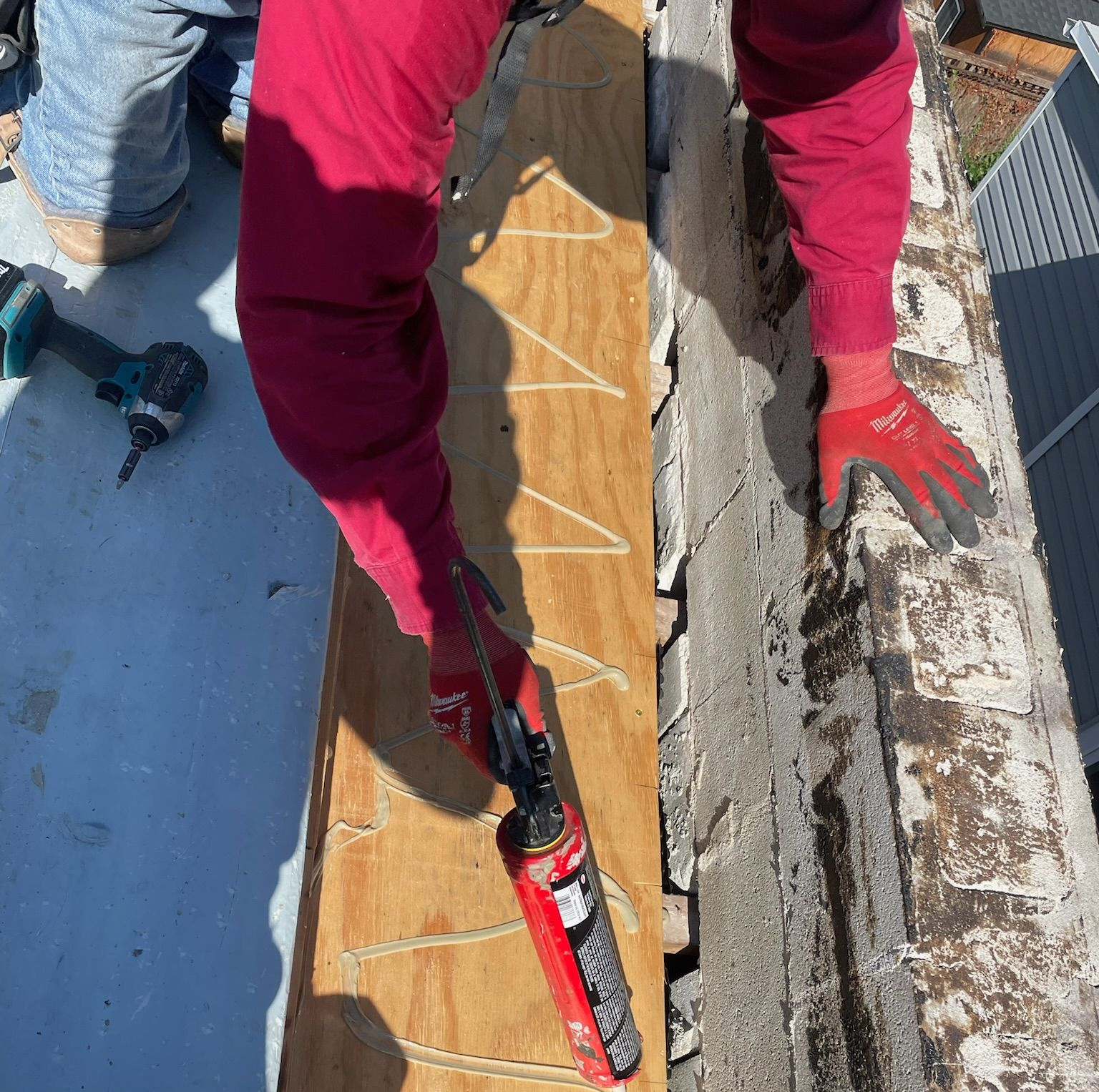 Worker applying caulk to a rooftop seam