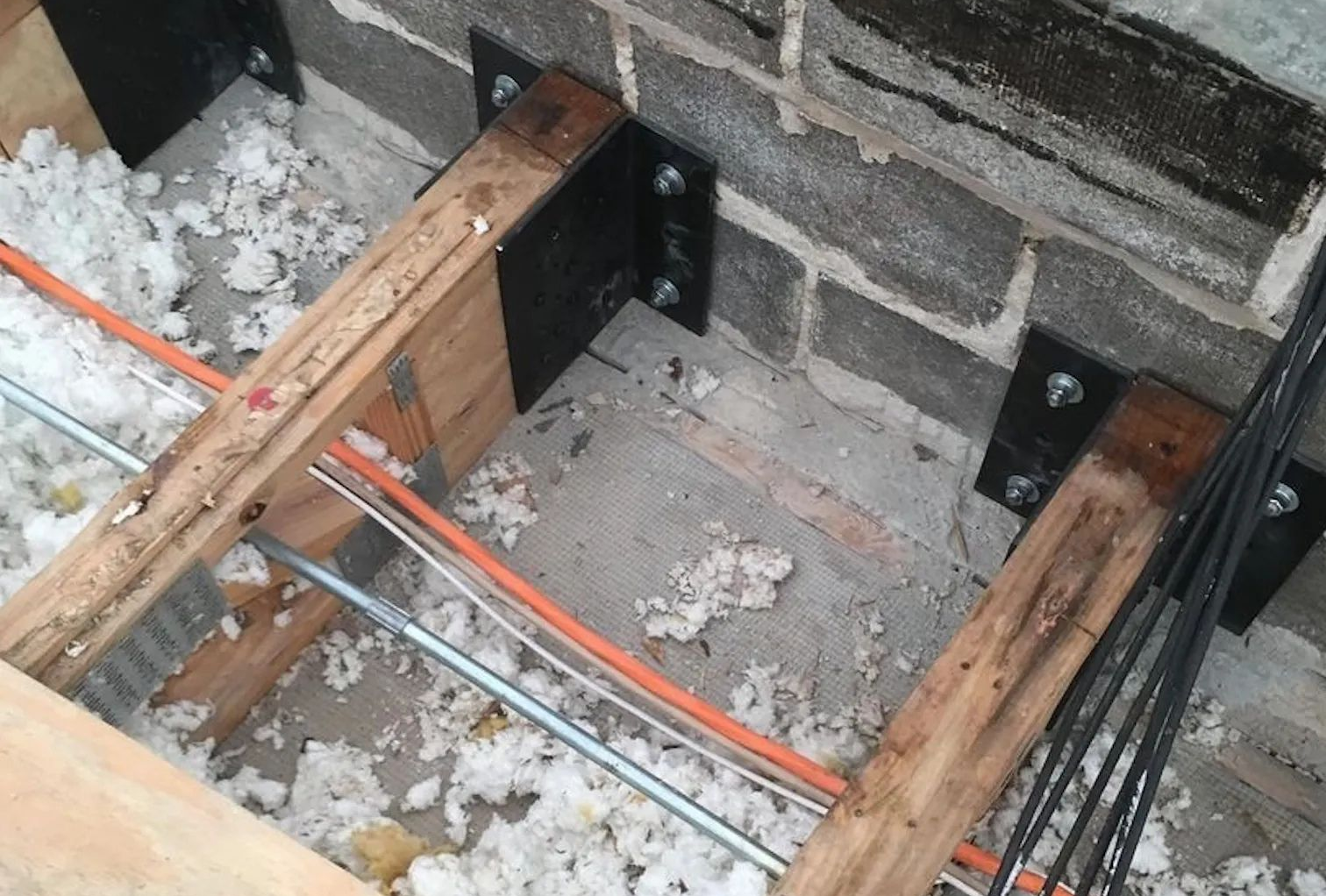 Wooden support beams and black steel brackets in an exposed rooftop floor