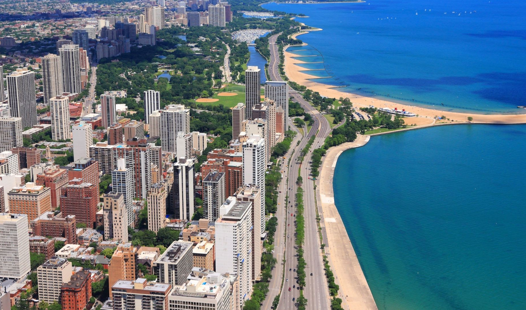 Aerial view of a coastal city skyline beside a sandy beach and blue ocean