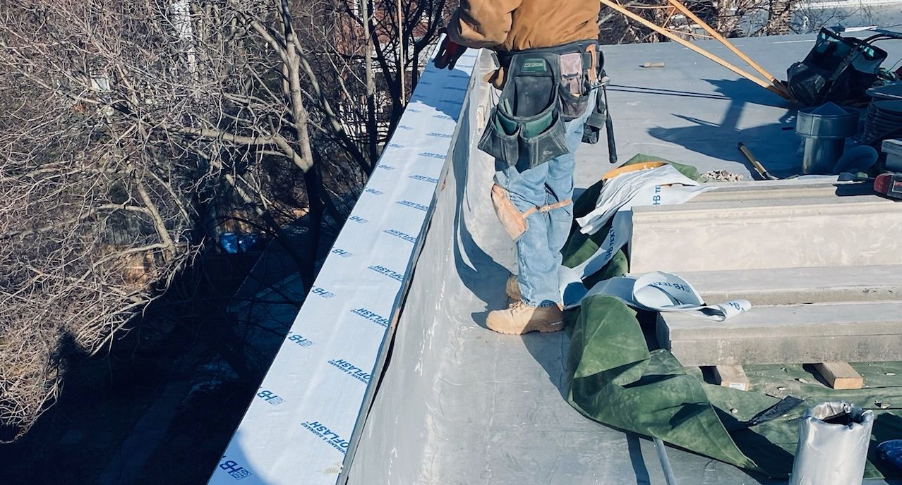 Workers installing flashing system on parapet wall
