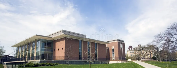 Modern brick campus building with large windows, glass entry, and grassy lawn