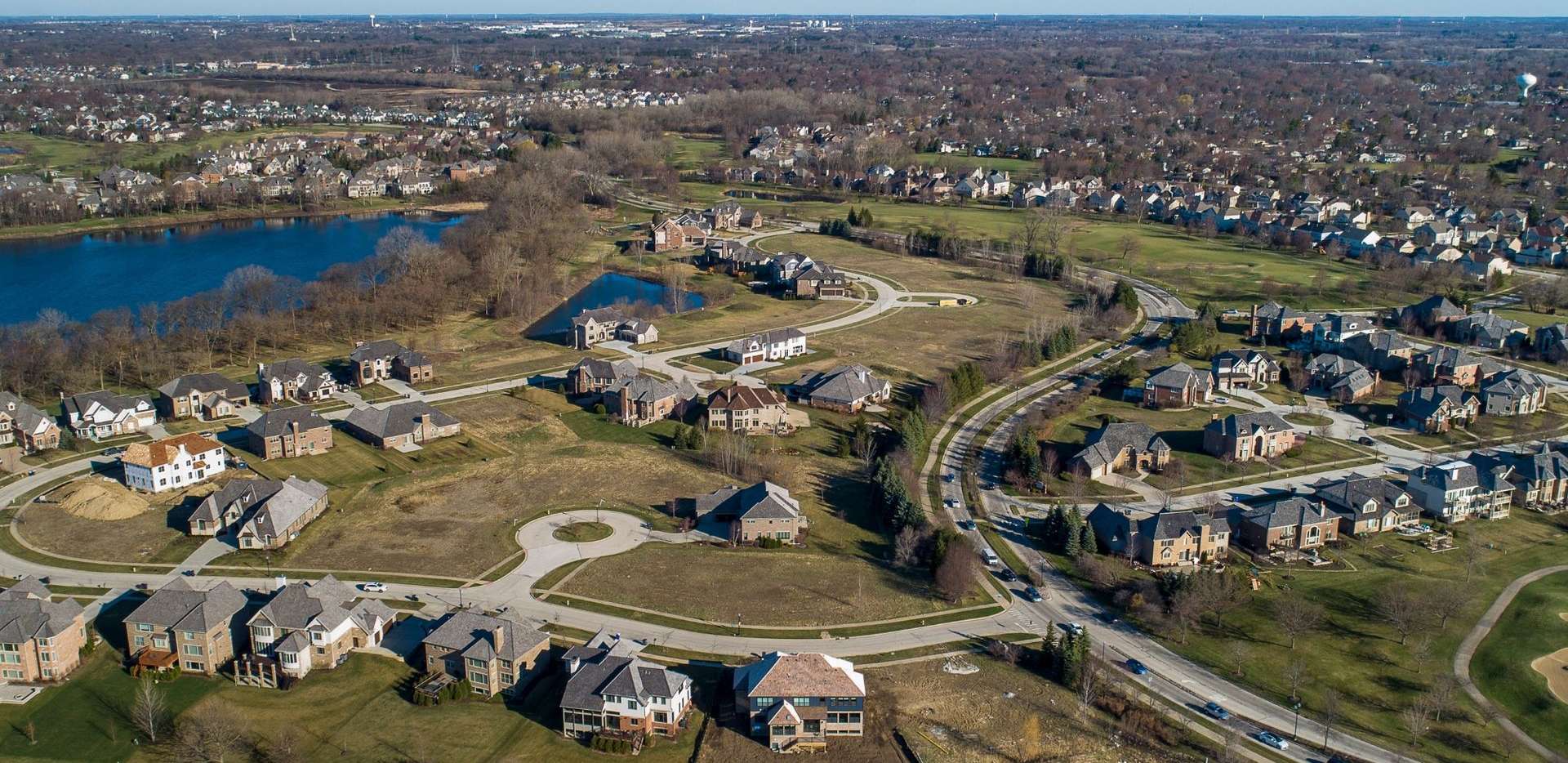 Aerial view of a suburban neighborhood(Libertyville) beside a blue lake and winding roads