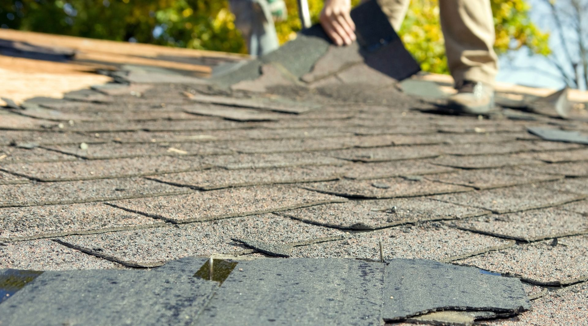 Roof shingles being removed by worker on a house rooftop