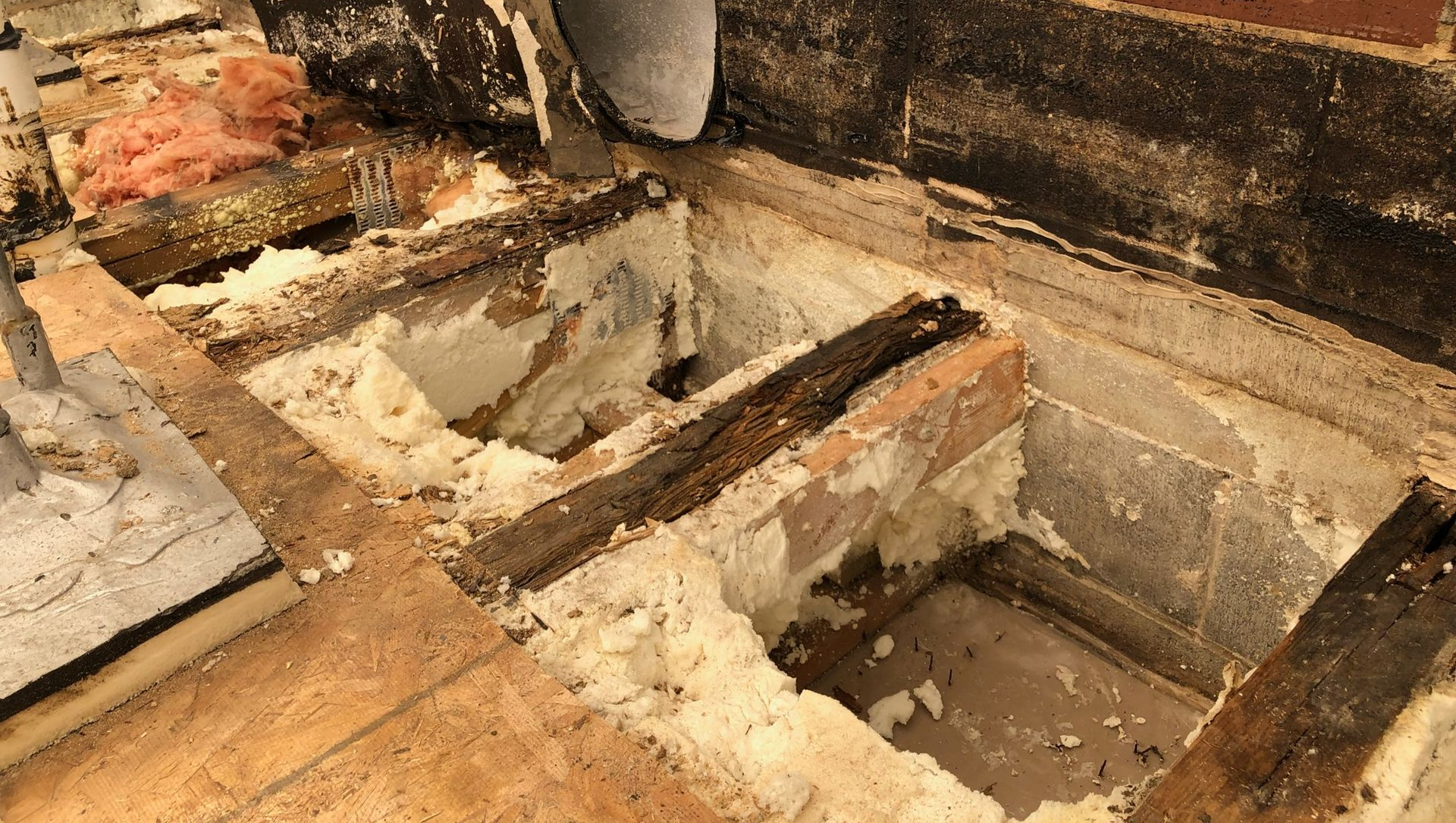 Brick and concrete foundation with debris in a damaged interior floor area