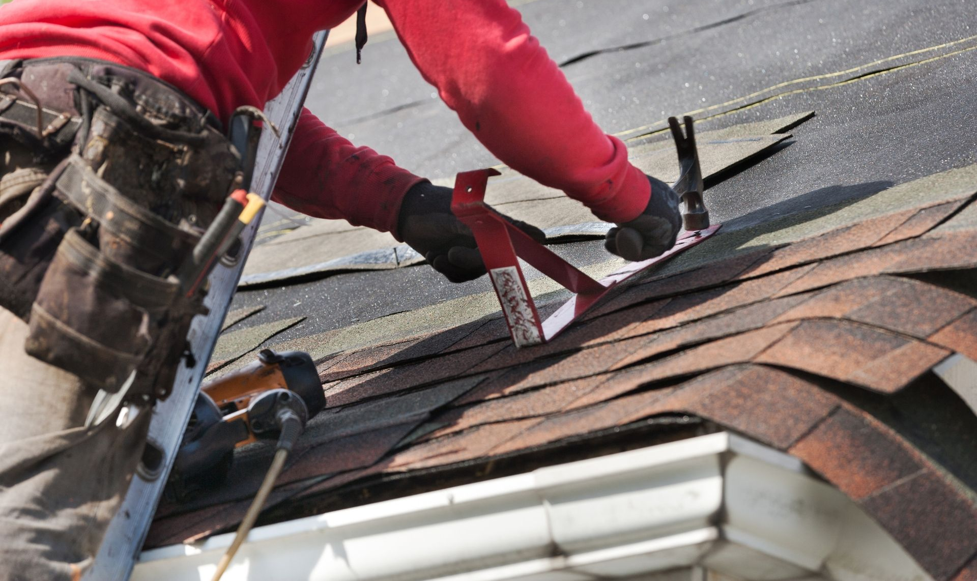 Worker installing roof shingles on a house roof