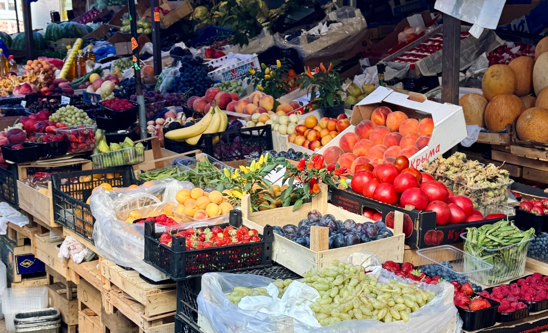 Outdoor market stall with colorful fruits and vegetables displayed in crates and baskets