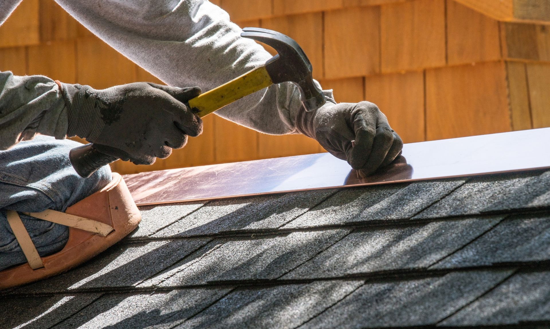 Worker hammering copper flashings on a roof