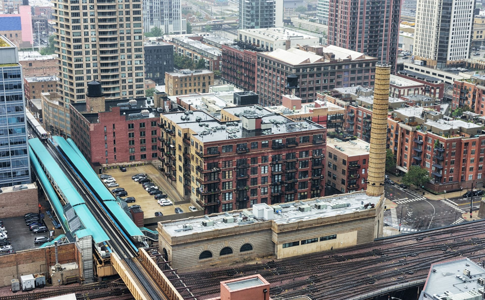 High-angle view of city buildings and construction site beside elevated train tracks