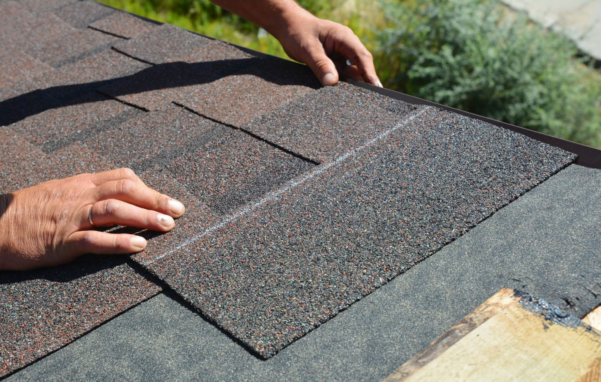 Worker laying shingles on a sloped roof