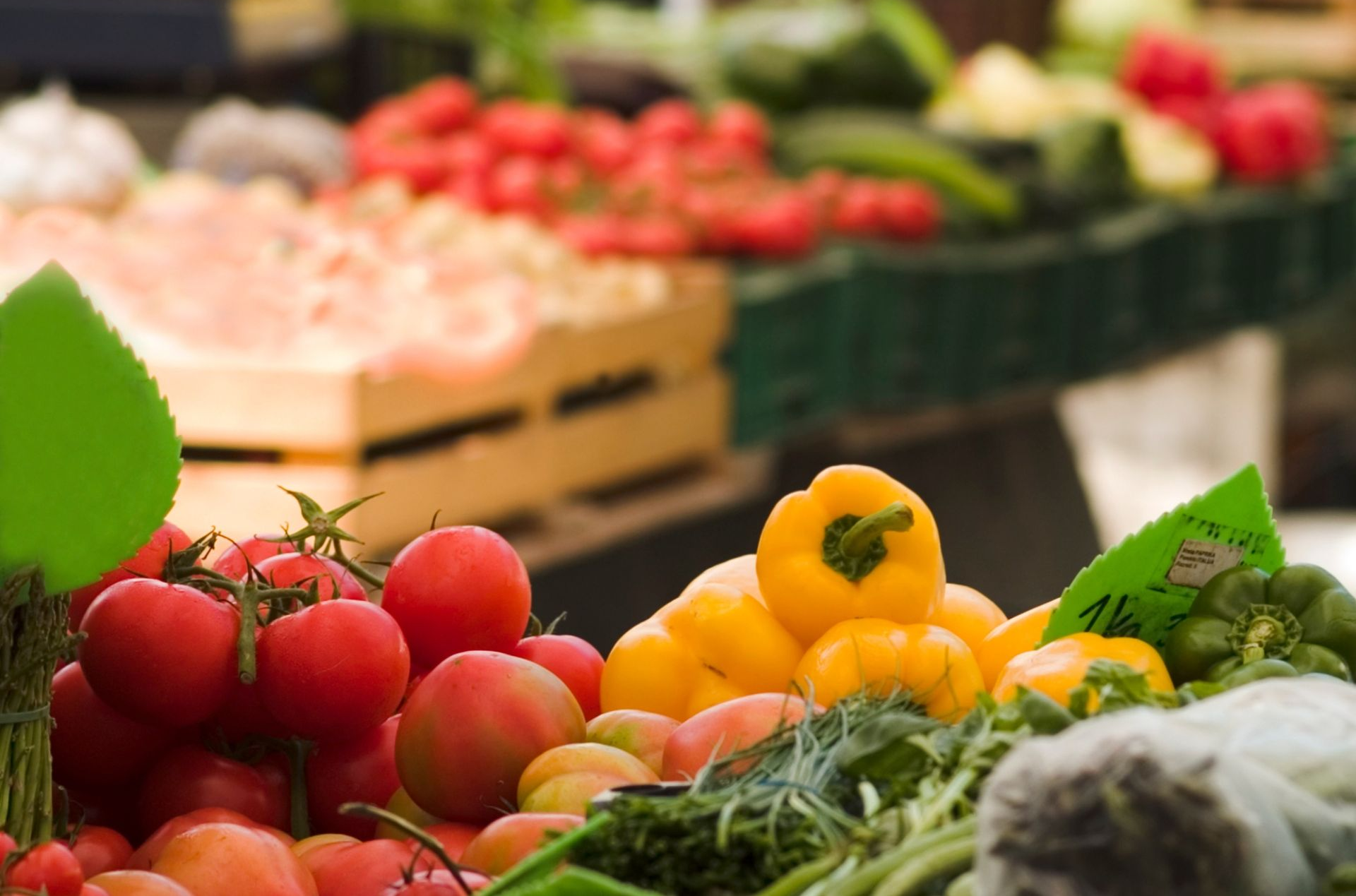 Fresh fruits and vegetables displayed at a market, including apples, oranges, herbs, and tomatoes