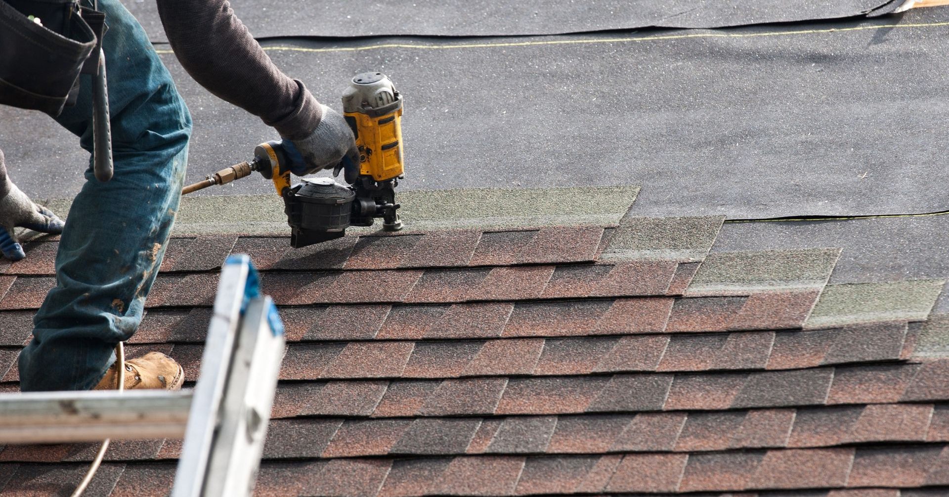 Worker installing shingles on a sloped roof