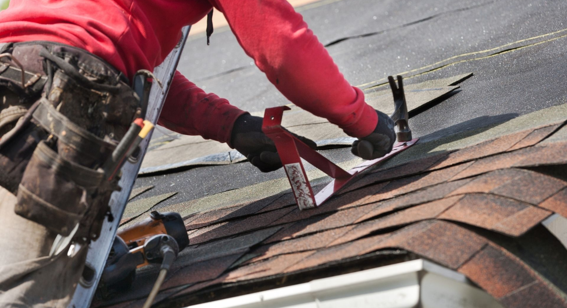 Worker installing new shingles on a sloped roof