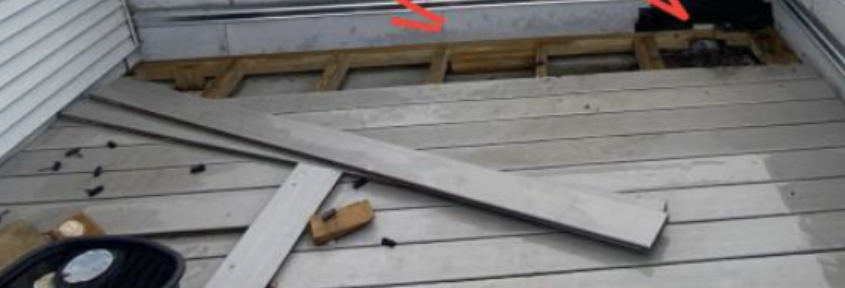 Wooden deck with loose boards and exposed insulation near a doorway
