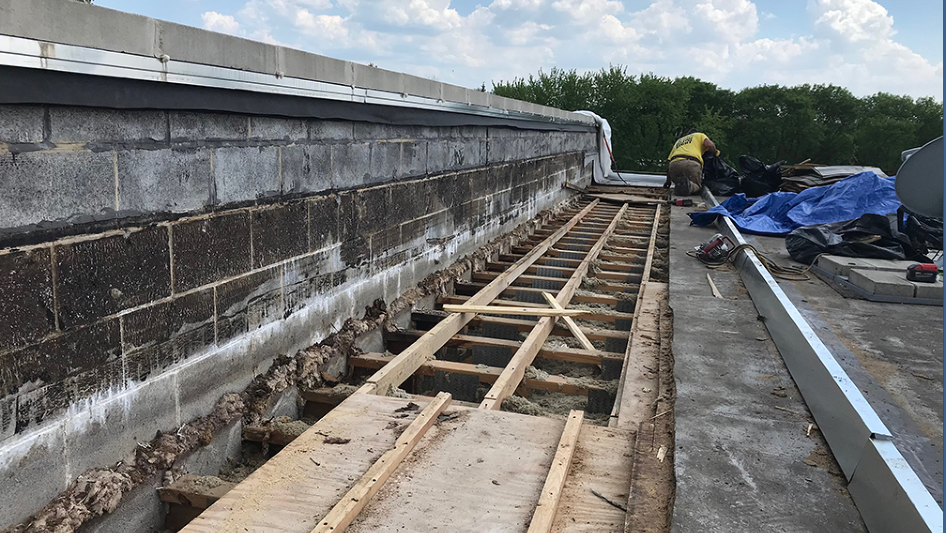 Rooftop construction area with exposed wooden framing floor beside a brick parapet wall