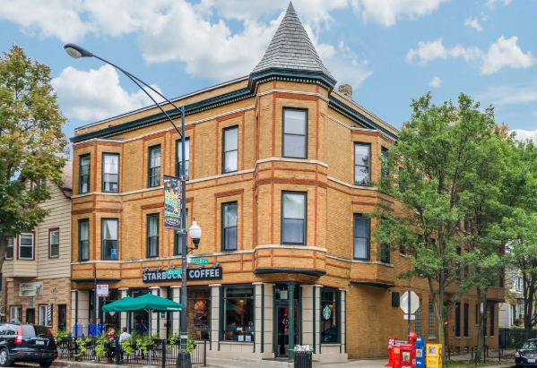 Corner brick coffee shop with outdoor seating on a tree-lined street
