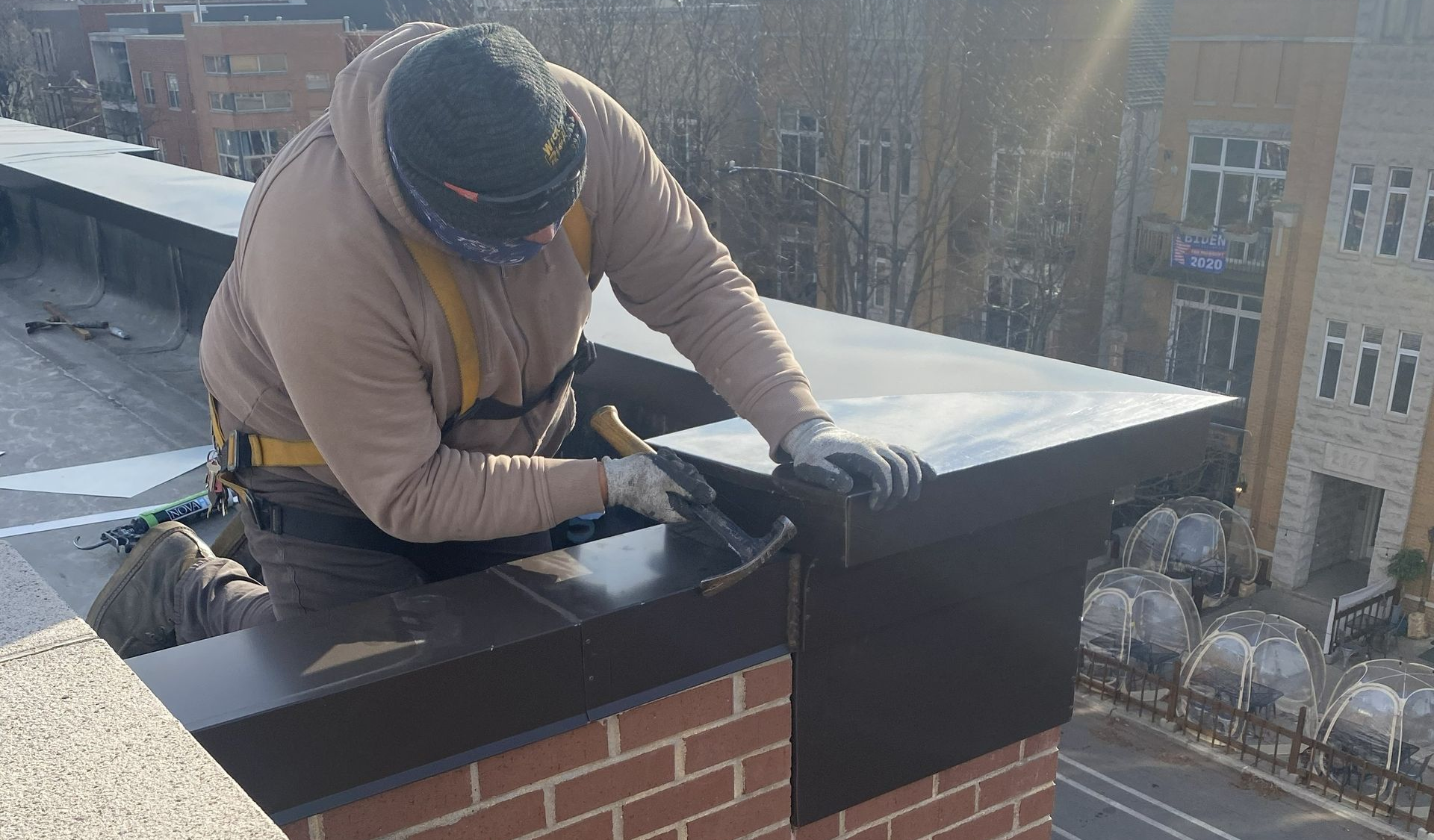 Worker installing black metal flashing on a rooftop