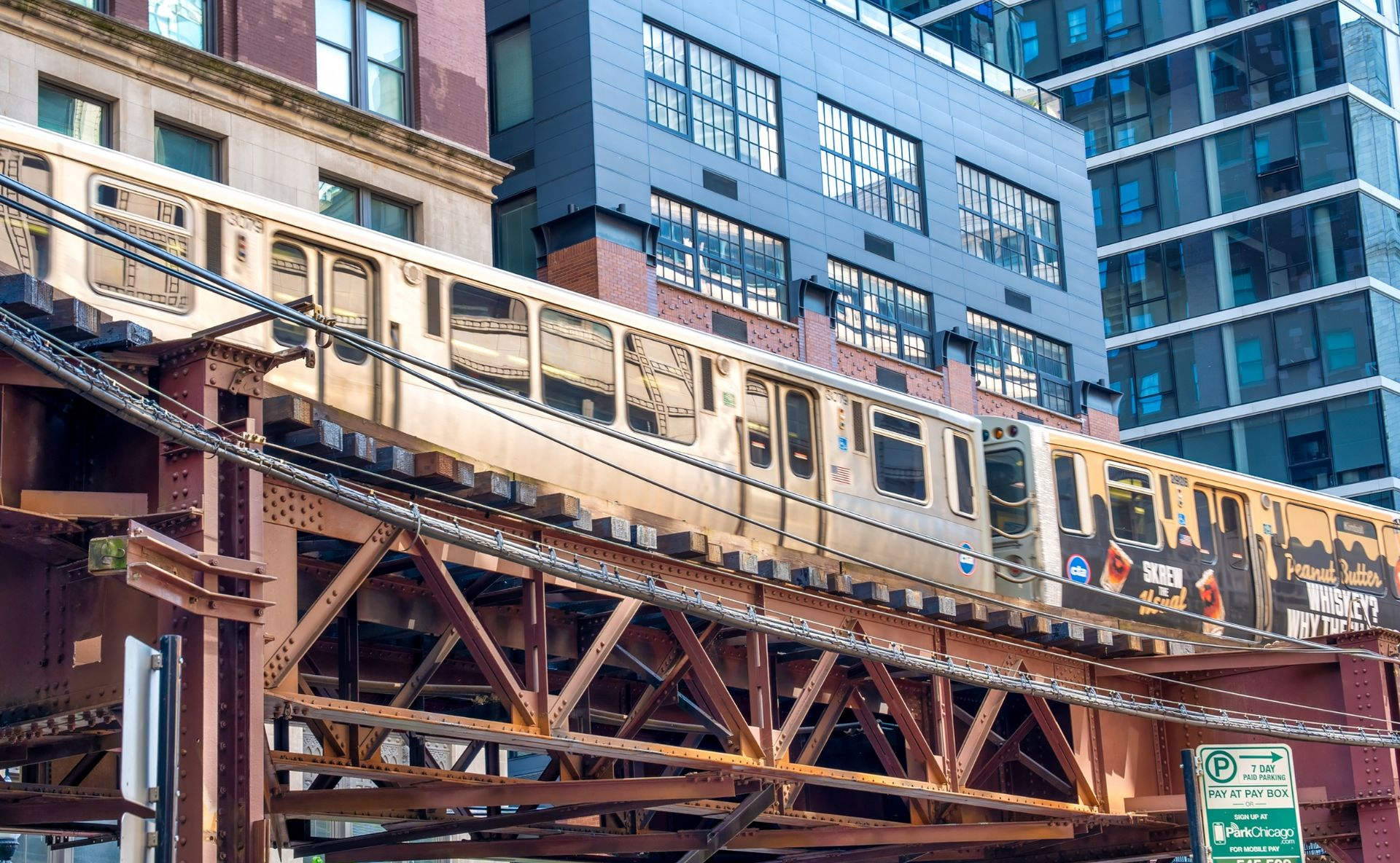 Elevated train crossing a steel bridge in front of modern apartment buildings in an urban area