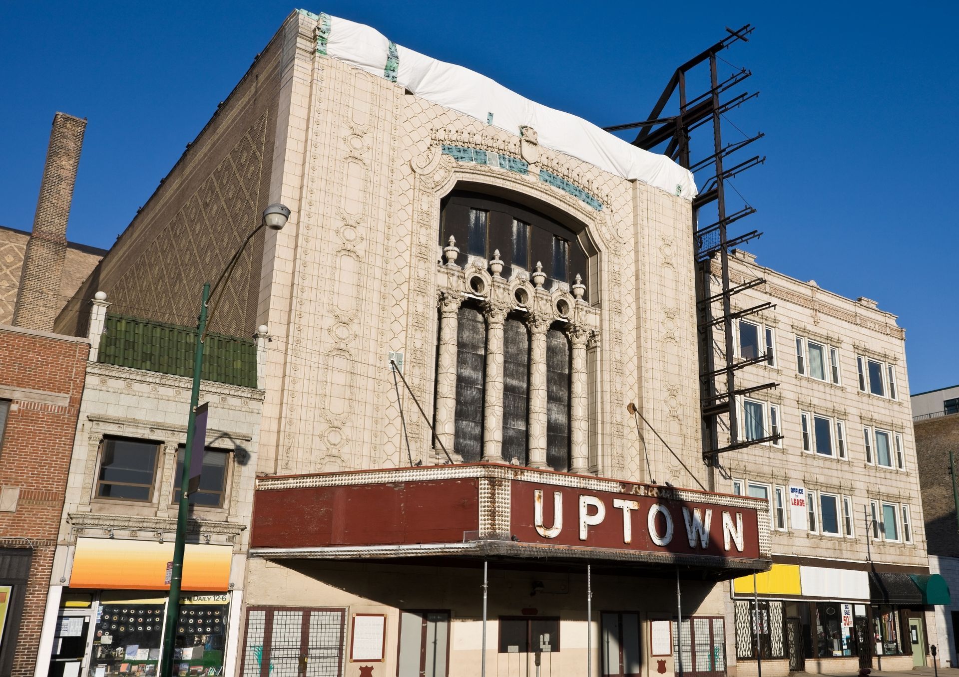 Historic Uptown theater facade with marquee and tall arched windows on a city street