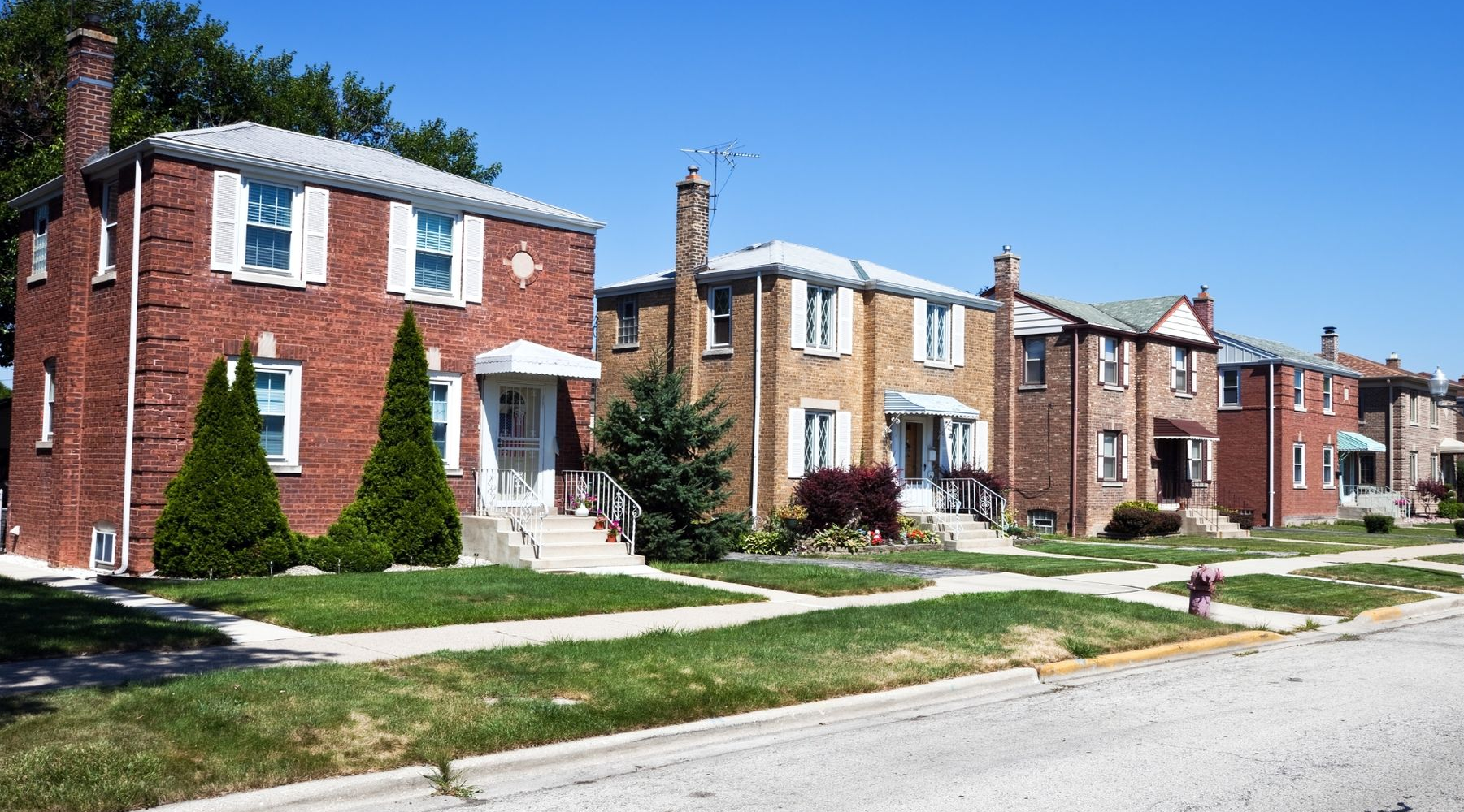 Row of brick houses with white trim along a quiet suburban street